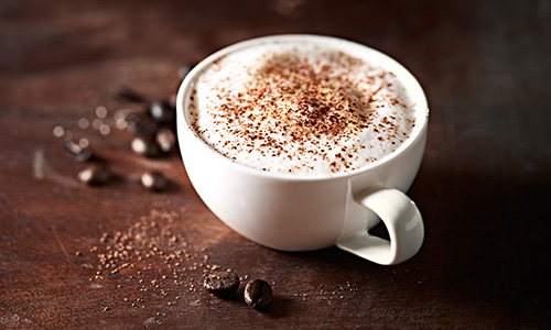 cappuccino with coffee beans on wood background